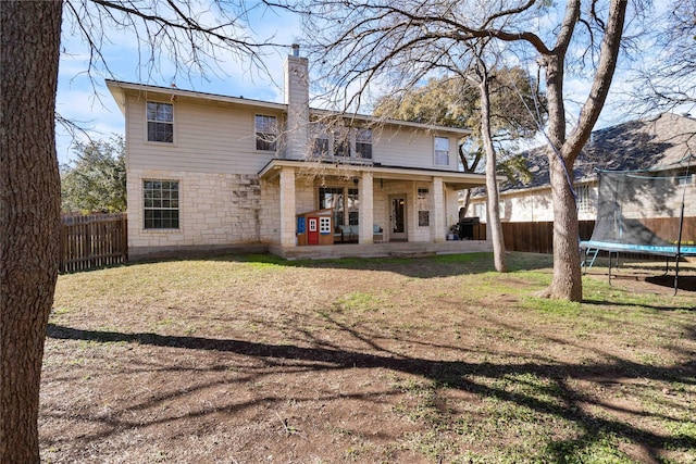 rear view of house with a patio, a trampoline, and a lawn