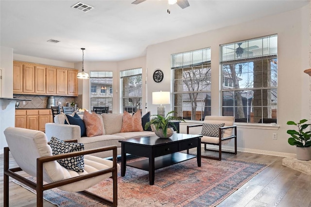 living room with a ceiling fan, baseboards, visible vents, and dark wood-type flooring