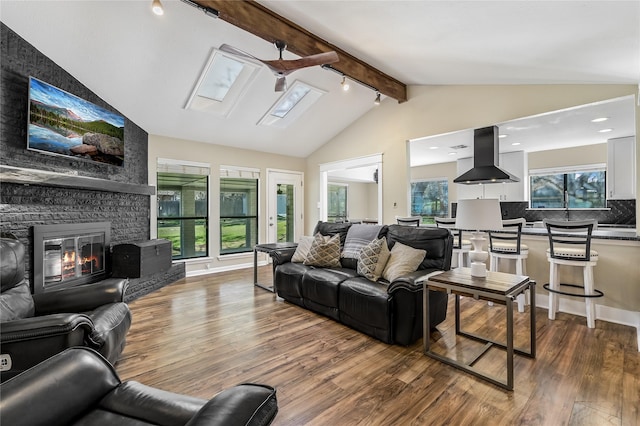 living room featuring a brick fireplace, vaulted ceiling with skylight, a wealth of natural light, and dark hardwood / wood-style flooring