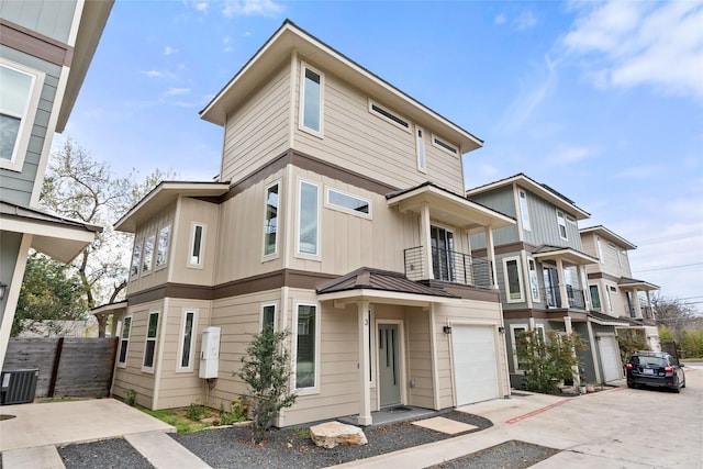 multi unit property featuring driveway, central AC unit, an attached garage, a standing seam roof, and board and batten siding