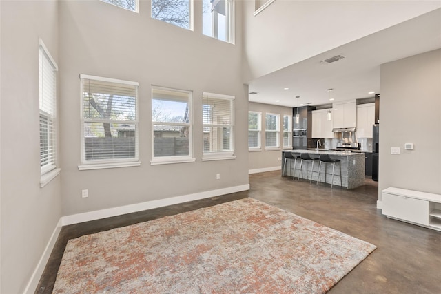 living room with a high ceiling, plenty of natural light, and sink