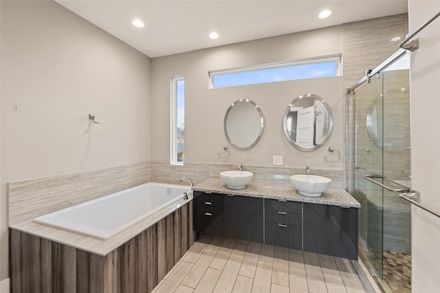 bathroom featuring a garden tub, a sink, and a shower stall