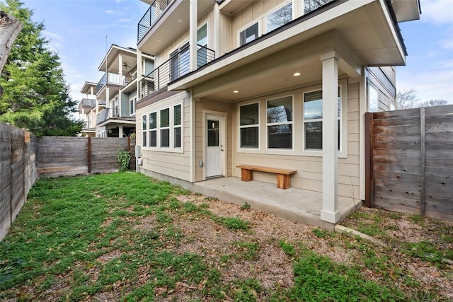 back of property with a fenced backyard and a balcony