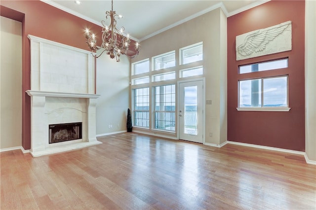 unfurnished living room featuring a chandelier, wood finished floors, ornamental molding, a fireplace, and baseboards