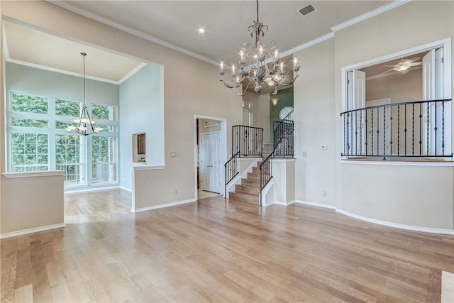 unfurnished room with a chandelier, stairs, wood finished floors, baseboards, and a towering ceiling