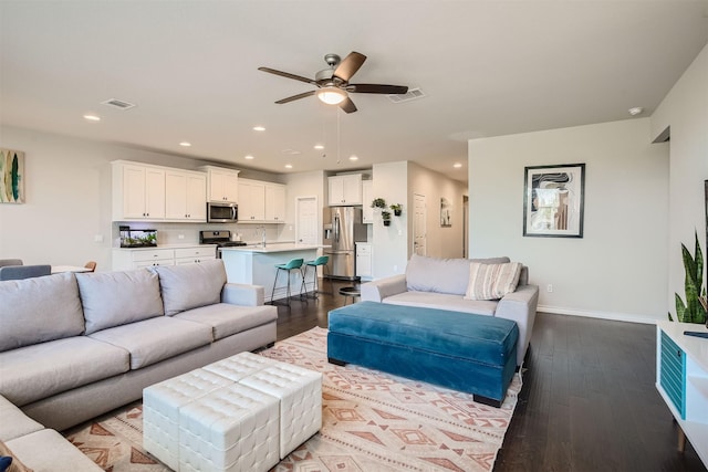 living room featuring ceiling fan and dark hardwood / wood-style flooring