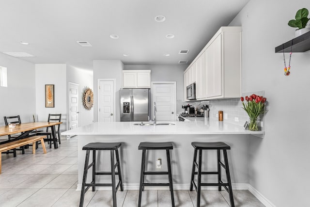 kitchen with white cabinetry, stainless steel appliances, tasteful backsplash, sink, and kitchen peninsula