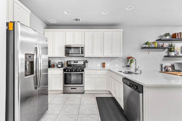 kitchen with tasteful backsplash, light tile patterned floors, sink, white cabinets, and stainless steel appliances