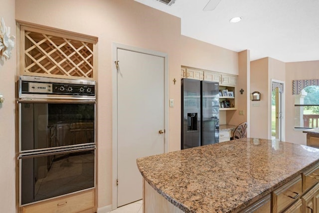 kitchen with stainless steel fridge with ice dispenser, a kitchen island, light stone counters, and double wall oven