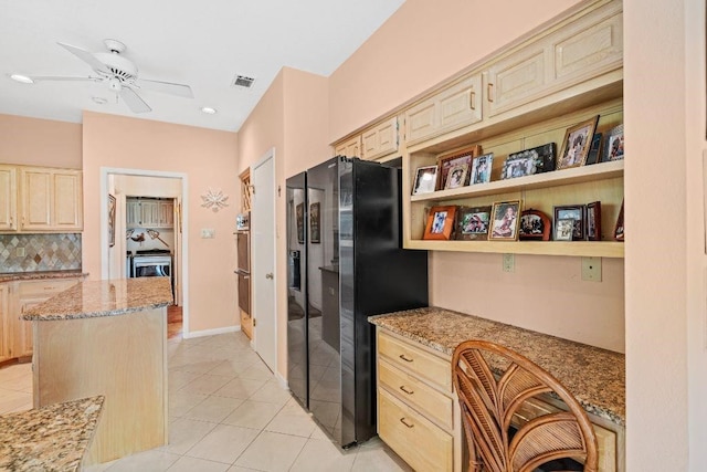 kitchen with built in desk, a center island, refrigerator with ice dispenser, and light stone counters