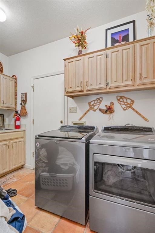 laundry room with cabinets, a textured ceiling, washing machine and dryer, and light tile patterned floors