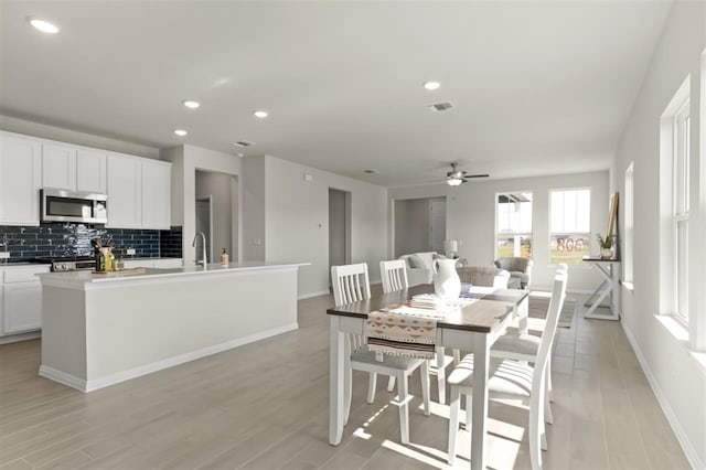 kitchen with tasteful backsplash, white cabinetry, sink, a kitchen island with sink, and stainless steel appliances