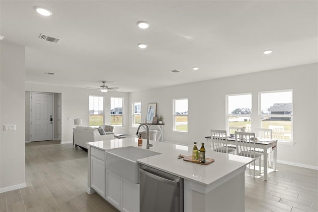 kitchen featuring sink, dishwasher, white cabinetry, an island with sink, and light wood-type flooring