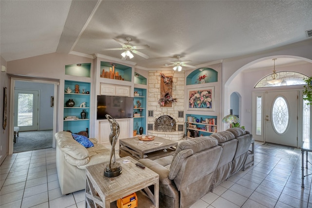 tiled living room with a textured ceiling, a fireplace, built in features, ornamental molding, and vaulted ceiling