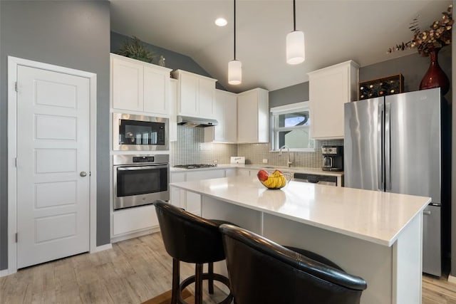 kitchen featuring appliances with stainless steel finishes, a sink, tasteful backsplash, light wood-style floors, and white cabinets