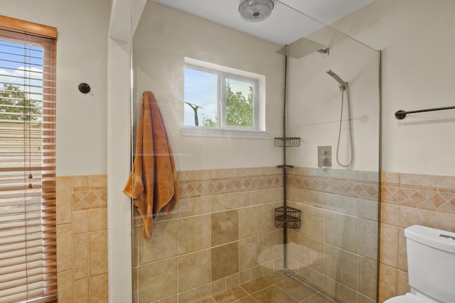 bathroom with toilet, tile walls, and a tile shower