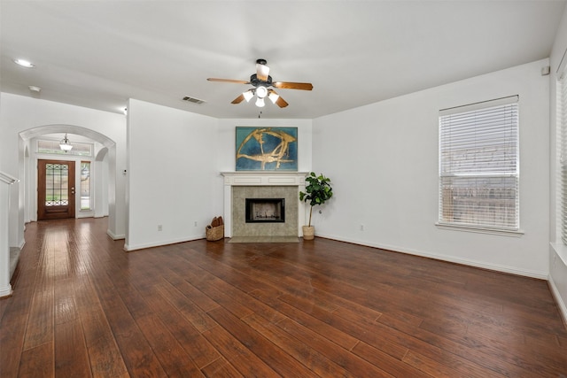 unfurnished living room with ceiling fan, dark wood-type flooring, and a tile fireplace