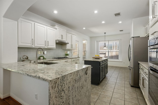 kitchen with sink, white cabinets, a center island, and light stone counters