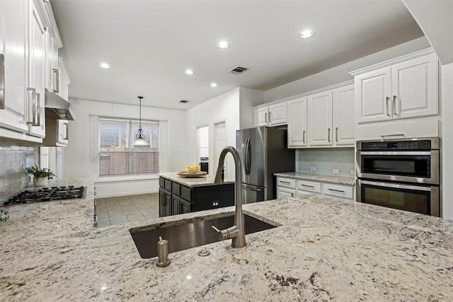 kitchen with light stone countertops, white cabinets, stainless steel appliances, tasteful backsplash, and sink