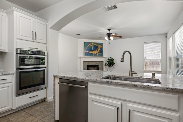 kitchen featuring light stone countertops, white cabinets, appliances with stainless steel finishes, sink, and light tile patterned floors