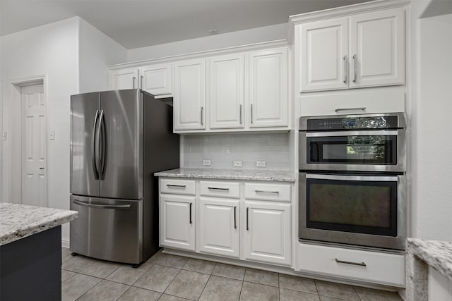 kitchen with light tile patterned floors, white cabinets, appliances with stainless steel finishes, and tasteful backsplash