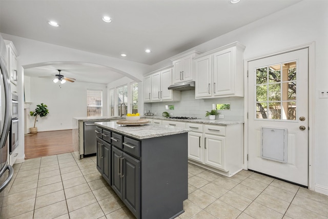 kitchen featuring white cabinets, a center island, stainless steel dishwasher, and light tile patterned flooring