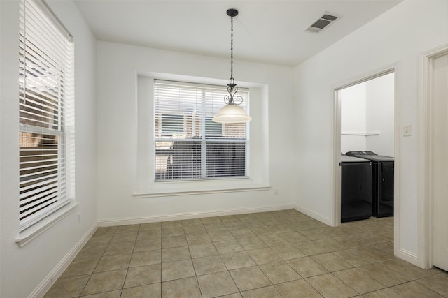 unfurnished dining area with a wealth of natural light, light tile patterned floors, and separate washer and dryer