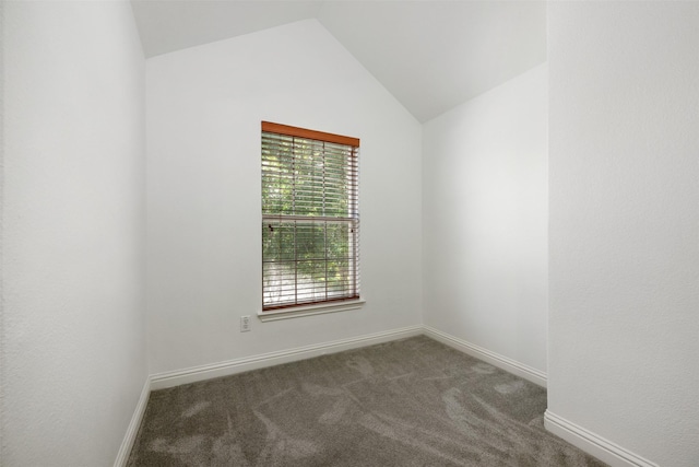 empty room featuring vaulted ceiling and dark carpet