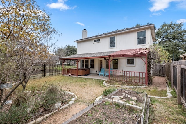 rear view of house featuring a patio and a hot tub