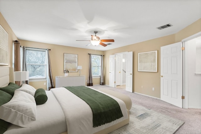 carpeted bedroom featuring multiple windows, radiator heating unit, connected bathroom, and ceiling fan