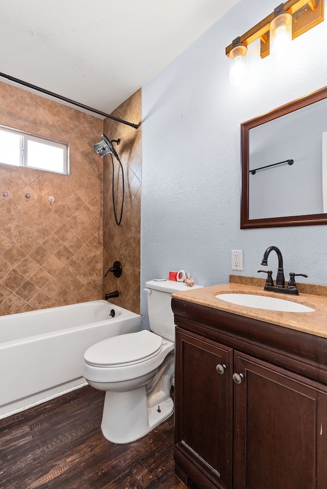 full bathroom featuring vanity, hardwood / wood-style flooring, tiled shower / bath, and toilet