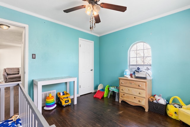 bedroom with ceiling fan, dark wood-type flooring, a nursery area, and crown molding