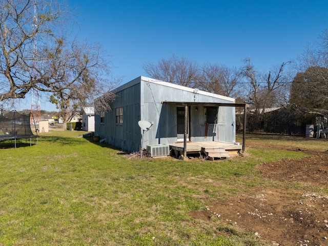 back of property featuring a yard and a trampoline