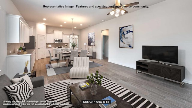 living room with ceiling fan with notable chandelier and light hardwood / wood-style floors