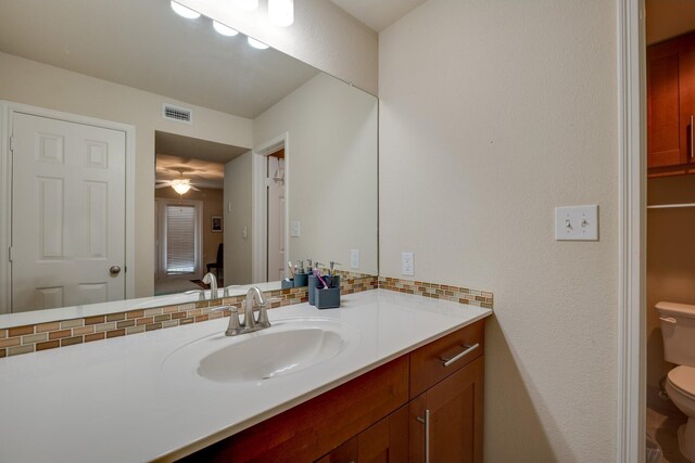 bathroom featuring tasteful backsplash, toilet, ceiling fan, and vanity