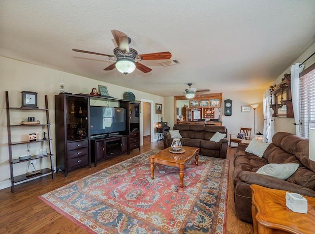 living room featuring ceiling fan, a textured ceiling, and dark hardwood / wood-style floors