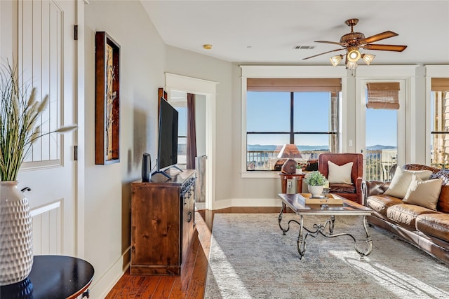 living room with dark wood-type flooring, plenty of natural light, and ceiling fan