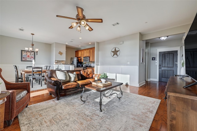 living room with ceiling fan with notable chandelier and dark hardwood / wood-style floors