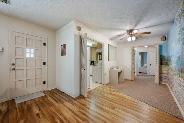 foyer entrance featuring light wood-type flooring, washer / clothes dryer, and a textured ceiling