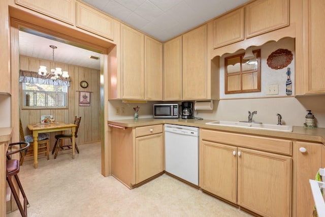 kitchen with dishwasher, sink, pendant lighting, wood walls, and light brown cabinets