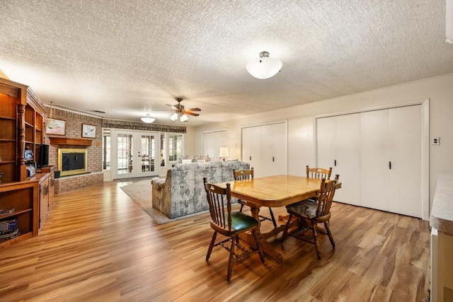 dining area featuring wood-type flooring, a textured ceiling, a fireplace, and french doors