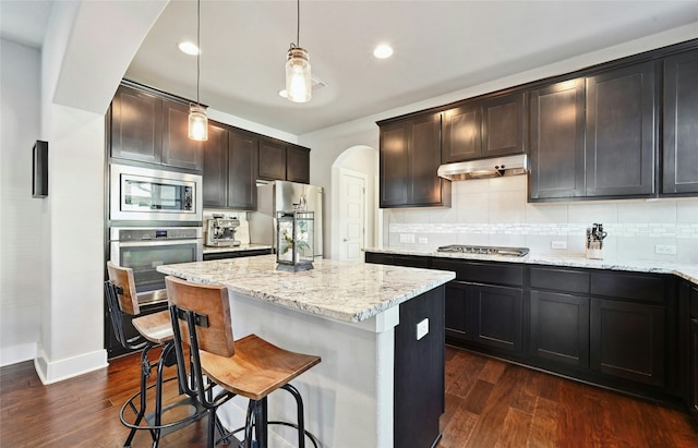 kitchen with hanging light fixtures, dark brown cabinets, dark hardwood / wood-style flooring, backsplash, and stainless steel appliances