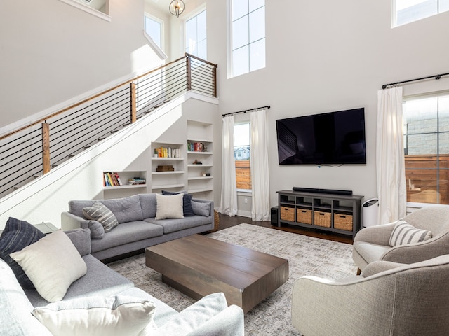 living room with built in features, light hardwood / wood-style flooring, and a high ceiling