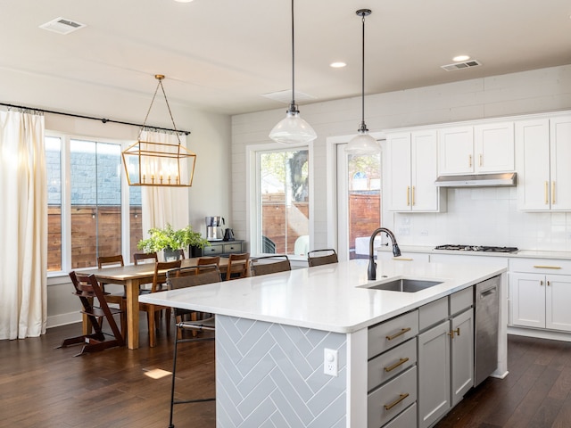 kitchen featuring decorative light fixtures, tasteful backsplash, an island with sink, sink, and dark hardwood / wood-style floors