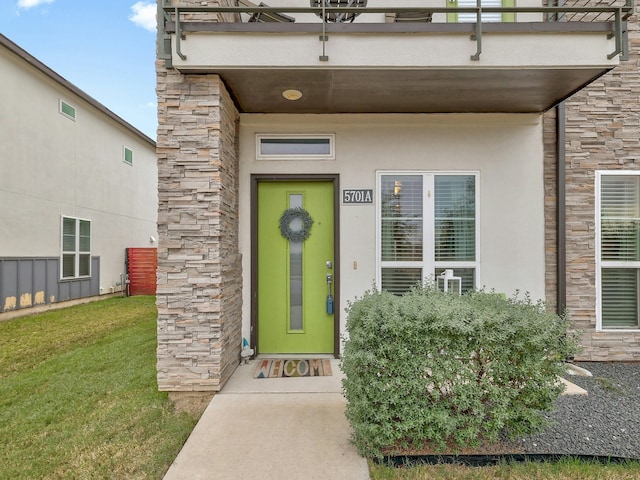 property entrance featuring a balcony and a yard