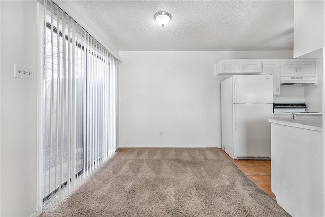 kitchen featuring a textured ceiling, light carpet, white cabinets, white refrigerator, and range with electric stovetop