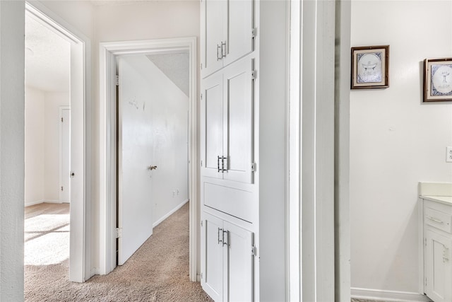 hall featuring a textured ceiling and light carpet