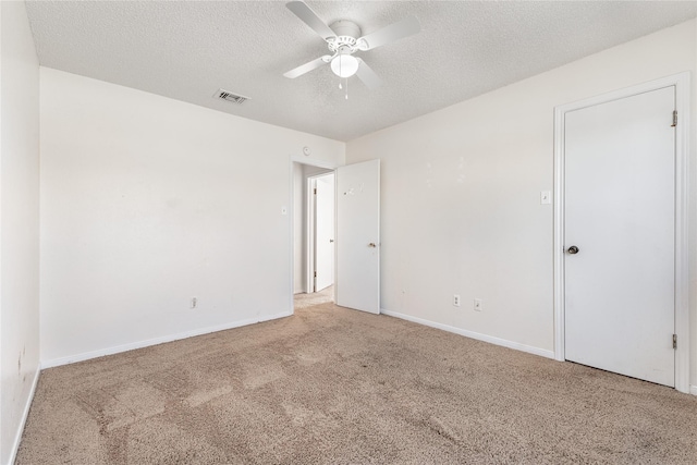 carpeted empty room with ceiling fan and a textured ceiling