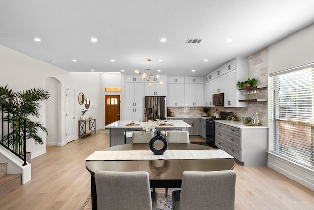 dining room with plenty of natural light, light hardwood / wood-style floors, and a chandelier