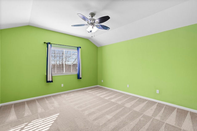 carpeted spare room featuring vaulted ceiling and ceiling fan